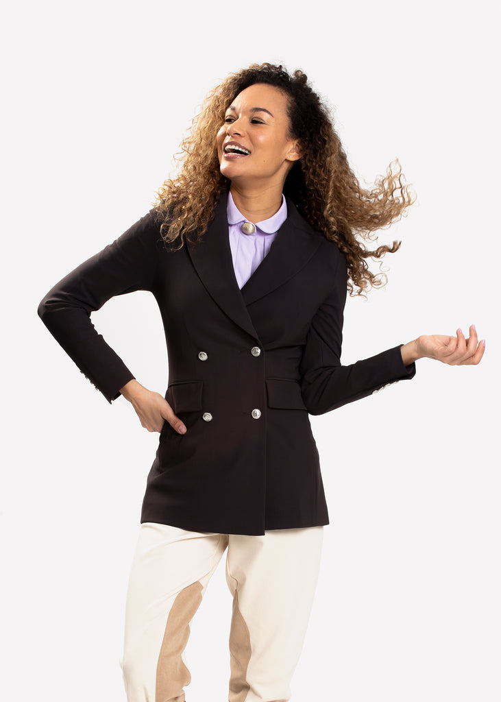 Laughing female model wearing a black equestrian blazer with metal buttons. 