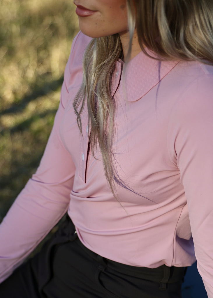 Detail image of woman wearing a pink shirt and brown trousers