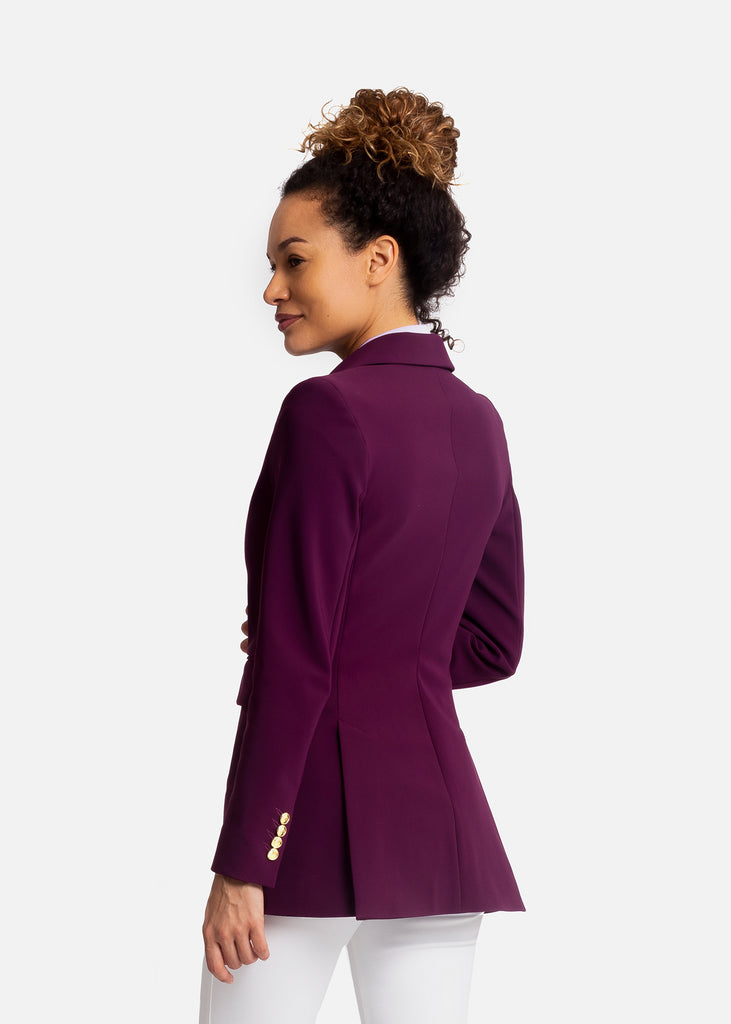 Photo of the back of a young woman in a studio. Wearing a lilac tailored blazer with white breeches.  