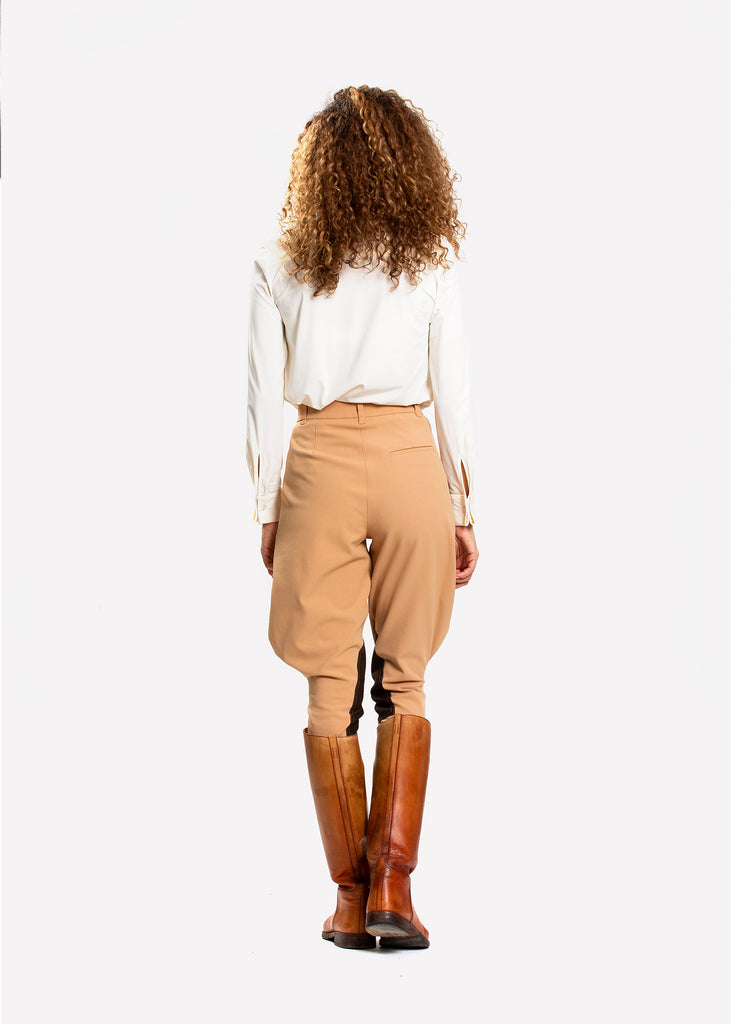 The back of a woman wearing a white shirt and beige jodhpurs. 
