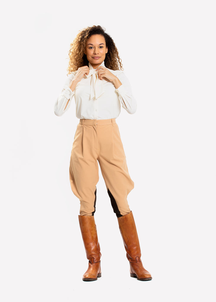 Woman in white blouse and tan loose fit riding breeches