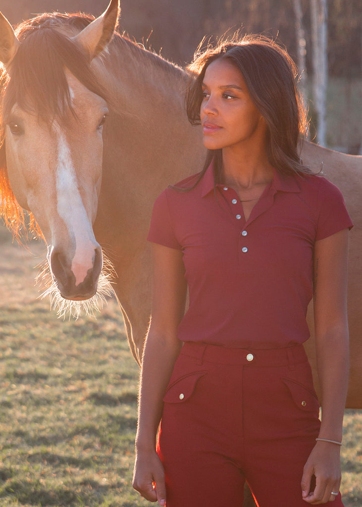 Girl in front of a horse wearing a short sleeve red pike shirt. 