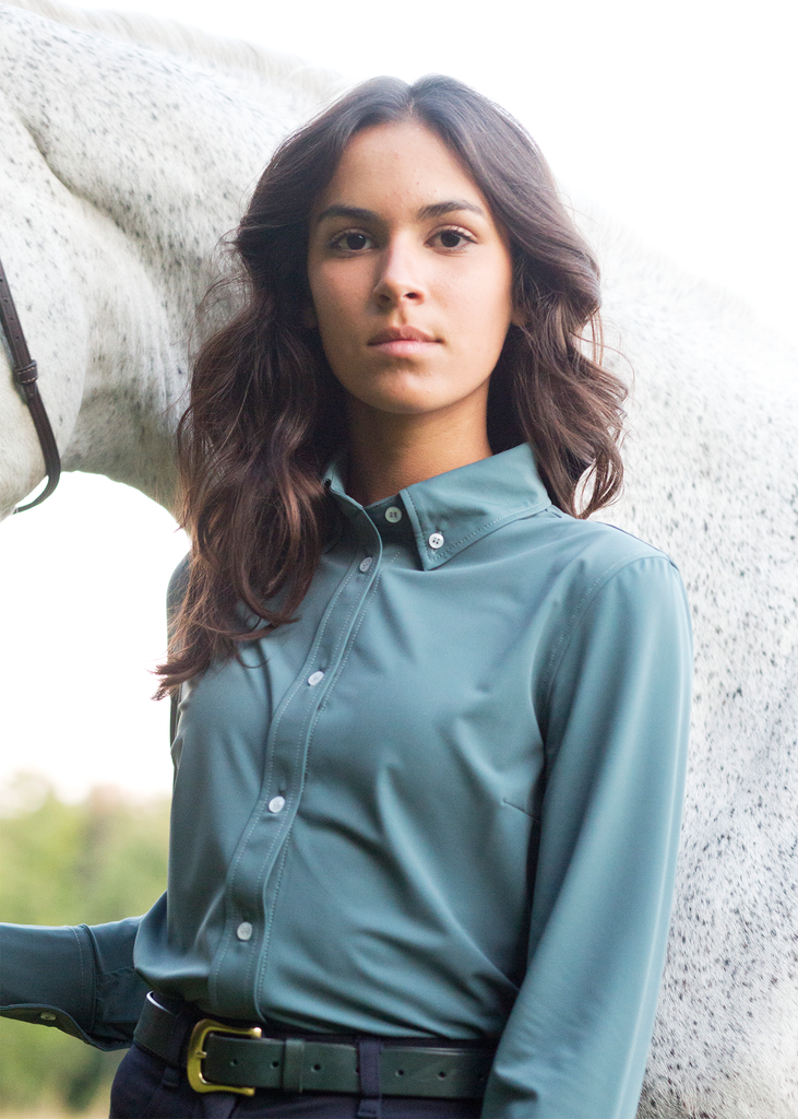 Girl in brown hair wearing a steel blue button down riding shirt. 