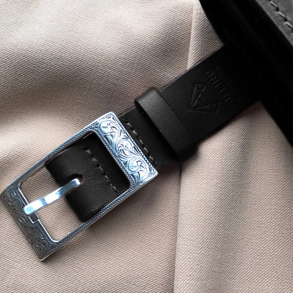 Close up on a black leather belt with engraved silver buckle