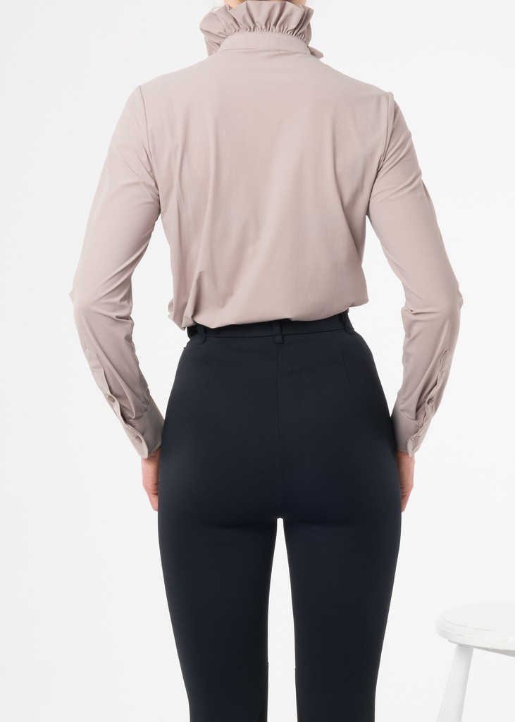 Model photographed from the back wearing black high rise riding breeches and a lilac blouse. 