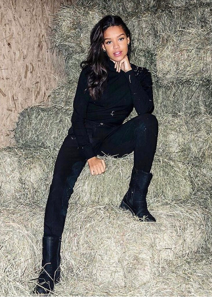 Young woman dressed in black sitting in a pile of hay