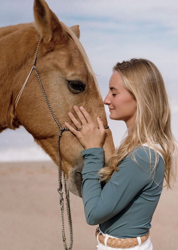 Blonde woman and a palomino horse on the beach