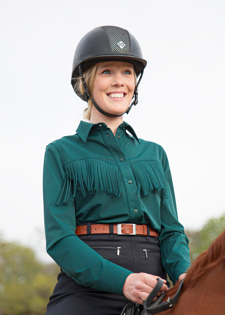Close-up on a smiling girl on a horse wearing a dark green shirt and black breeches