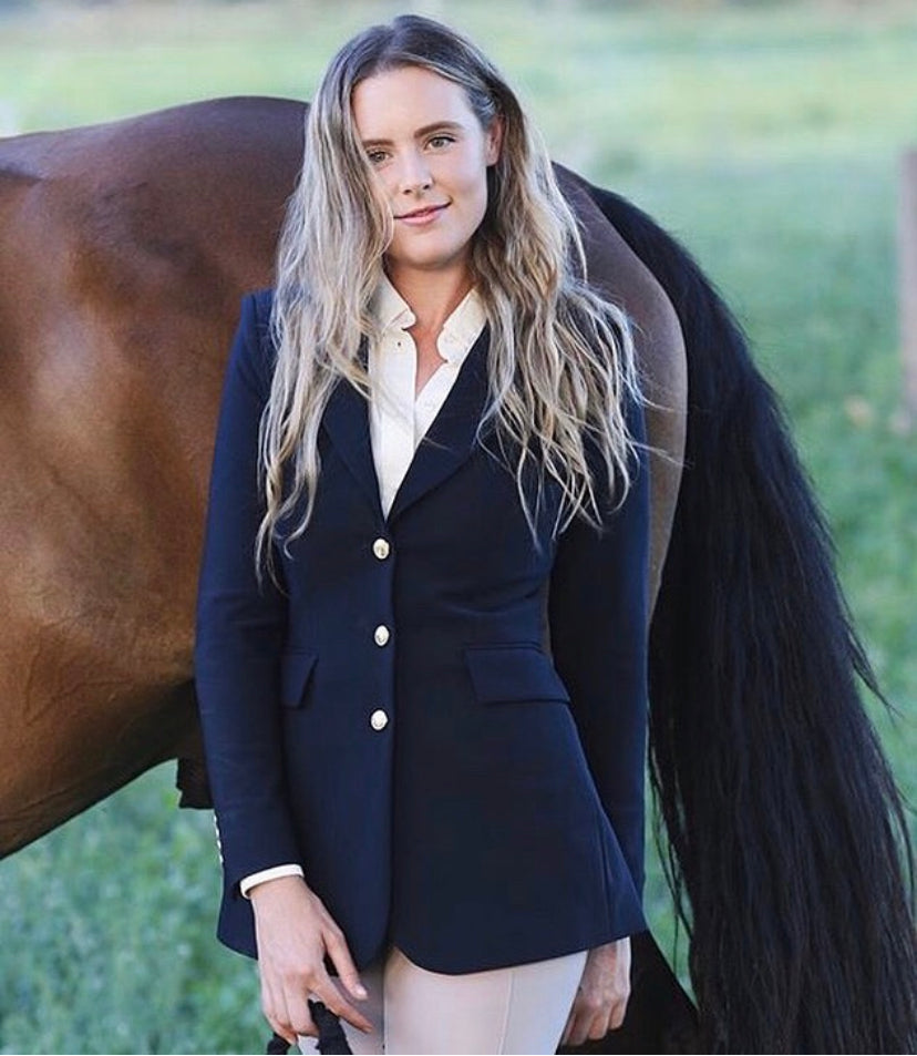 Smiling woman with long blonde hair dressed in a navy blazer with gold buttons