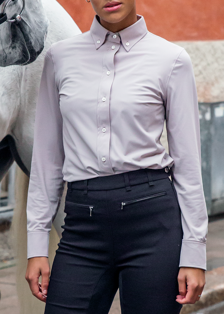 Model standing in front of a horse wearing a lilac equestrian shirt. 