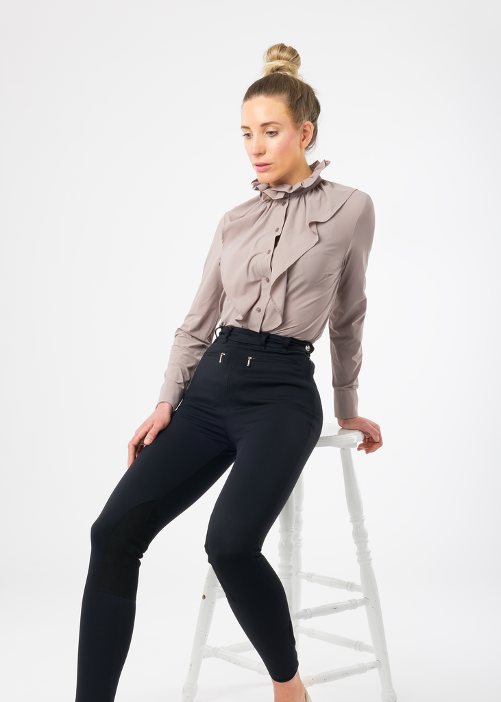 Model sittning on a chair in high waist black riding breeches.