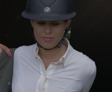 Event rider in a green show jacket and beige riding breeches. 